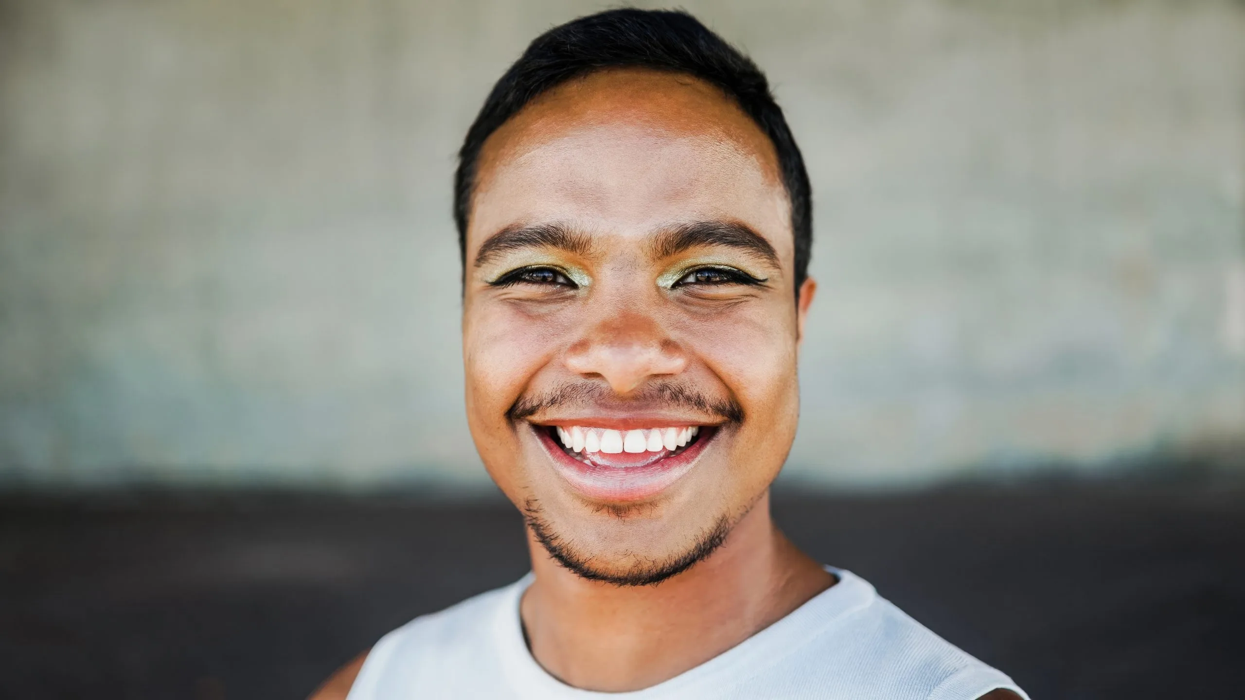 Smiling man in white t-shirt with visible bright teeth and clear skin
