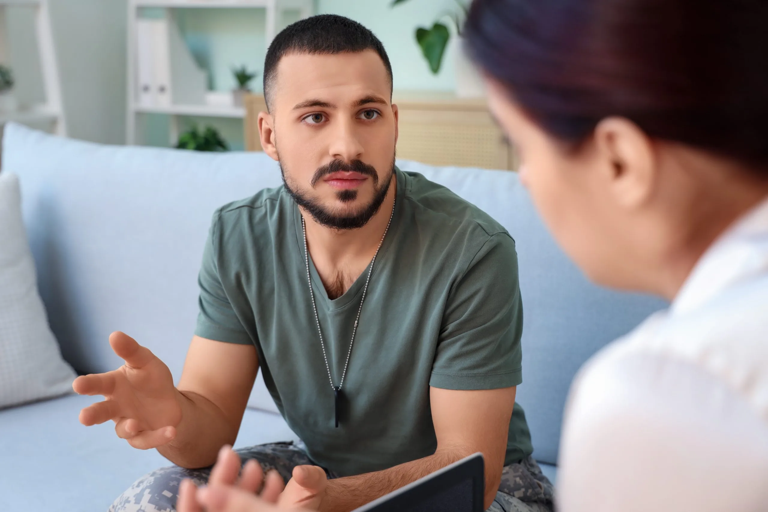 Healthcare provider in green shirt discussing treatment with patient holding tablet during consultation