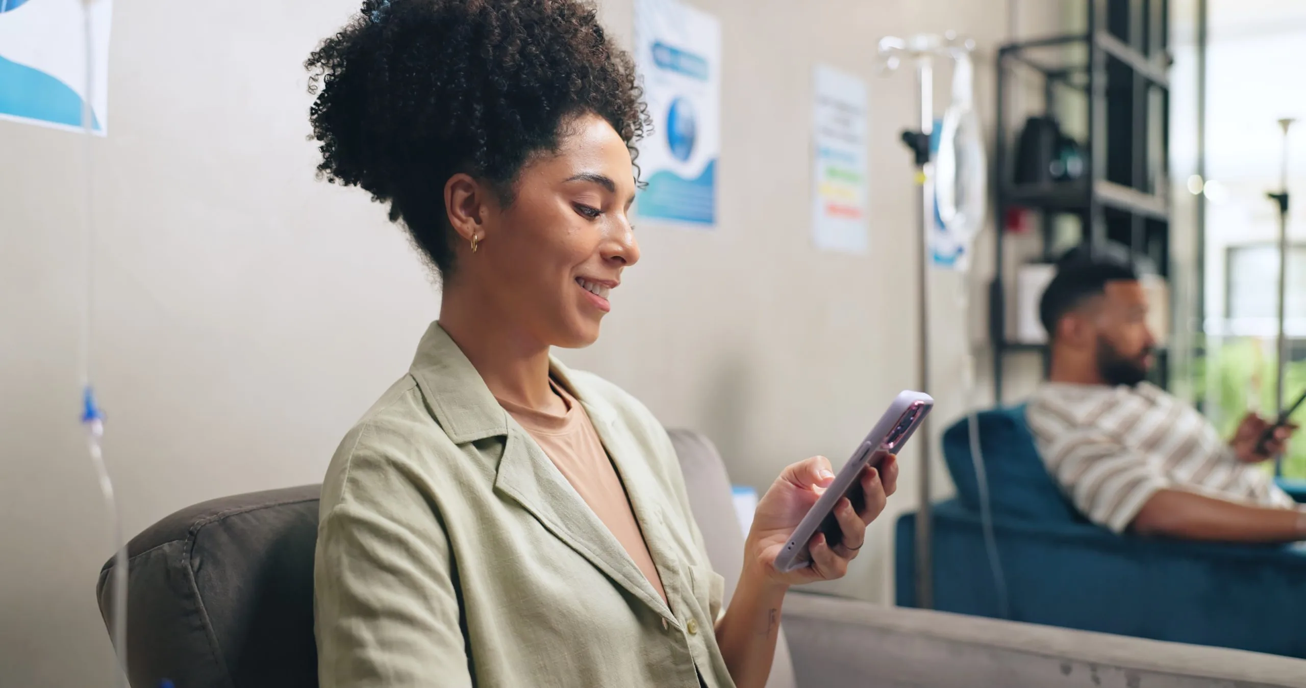 Woman in beige blazer smiling while holding smartphone at office reception desk