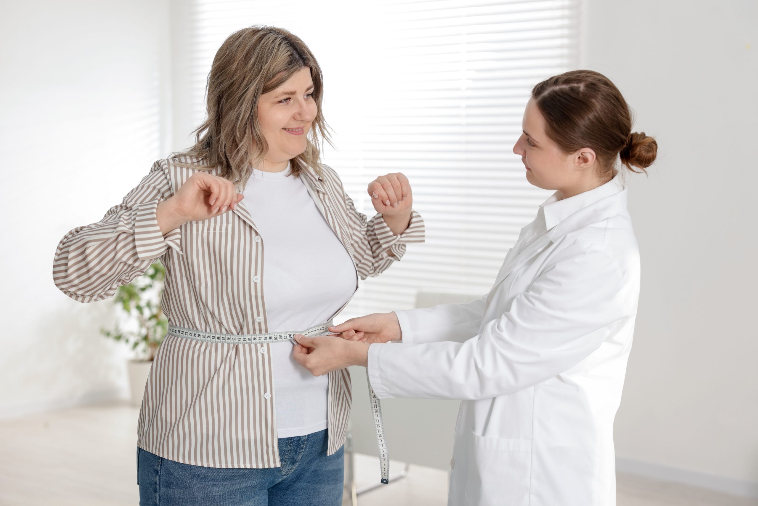 Healthcare provider measuring waist of patient using tape measure