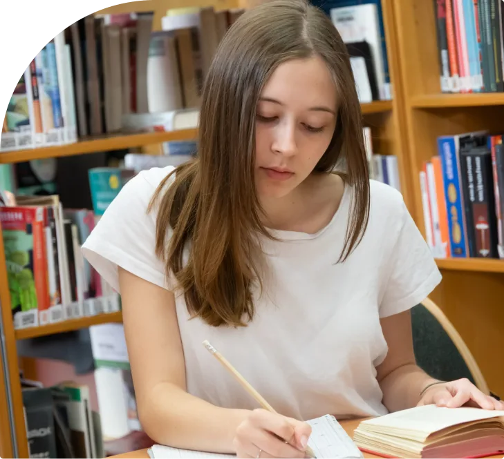 Teenage girl focused on studying with open book in library setting