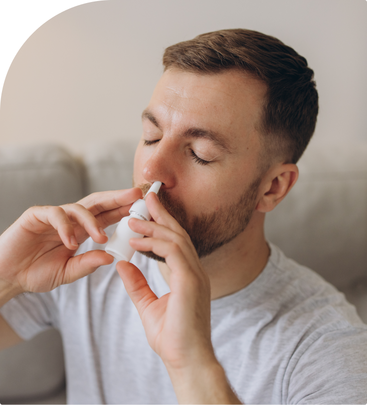 Man using nasal spray with eyes closed in home setting