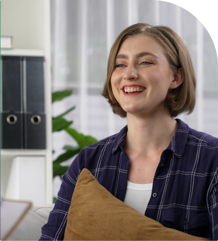 Woman in plaid shirt smiling in modern office with plant and filing cabinets