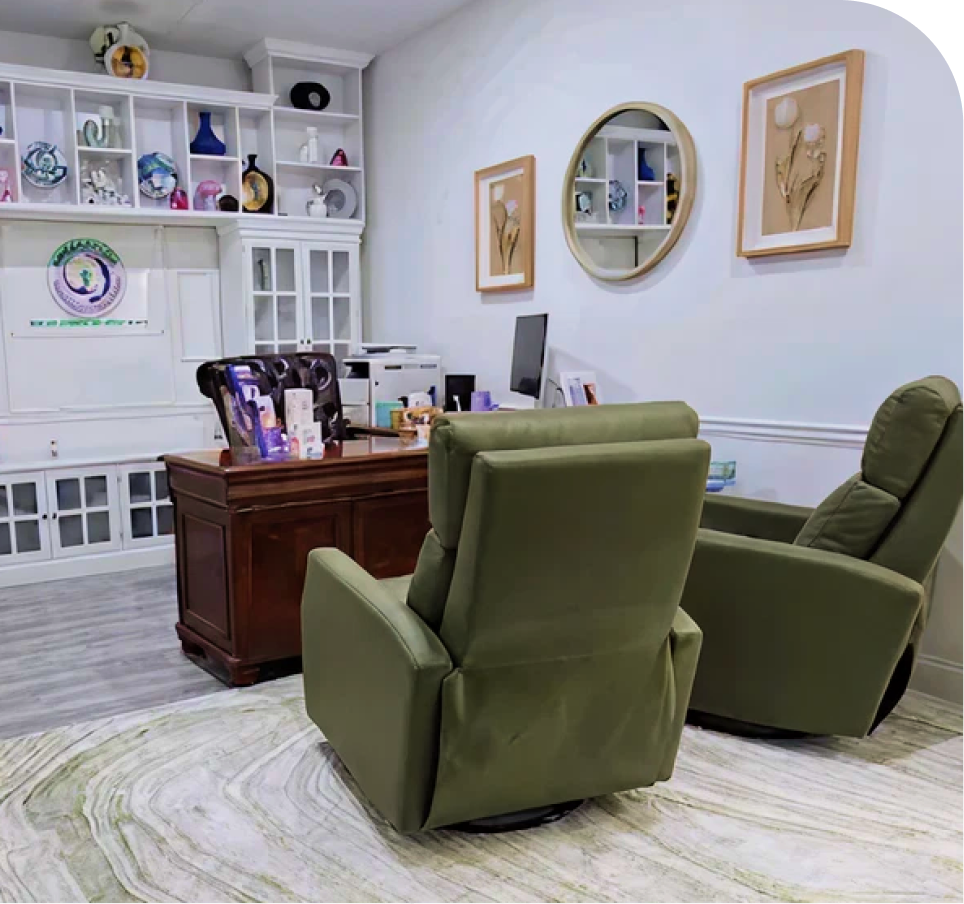 Mental health office interior with green armchairs, wooden desk, white shelving, and framed botanical artwork