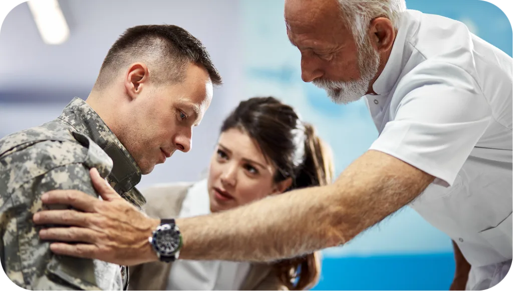 Healthcare provider examining military service member's shoulder while another provider observes