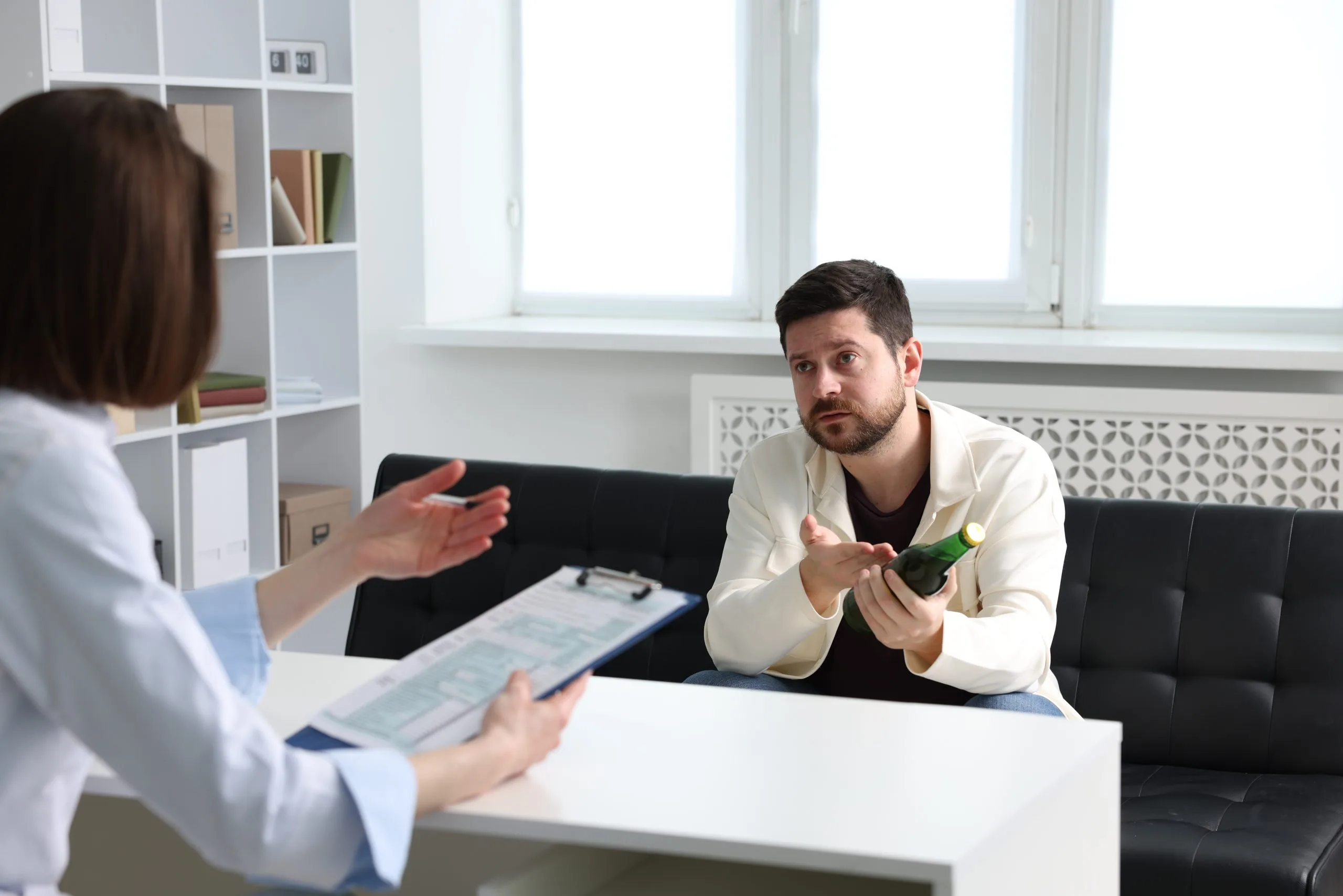 Male clinician discusses treatment plan with female patient holding paperwork across desk