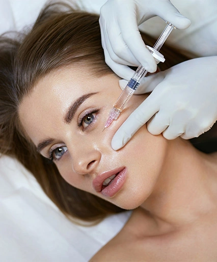 Practitioner injecting dermal filler into patient's cheek area