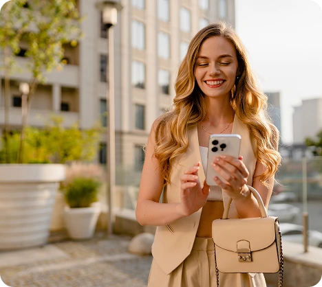 Woman in beige blazer holding smartphone on urban rooftop with city skyline backdrop
