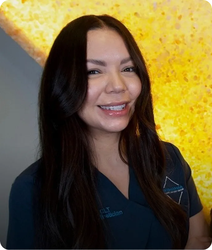 Valerie Castillo, staff member in dark blue scrubs, smiling at camera against yellow textured background