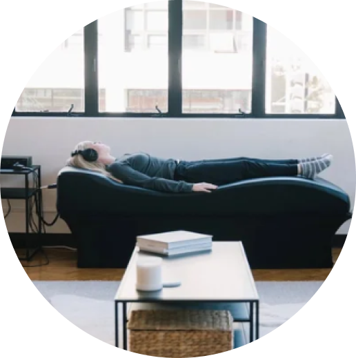 Person relaxing on black sofa in bright wellness space with large windows