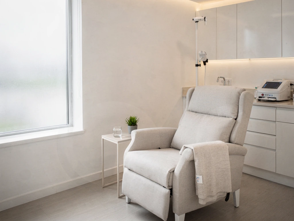 Modern aesthetic treatment room with beige reclining chair, medical device on countertop, and minimalist furnishings
