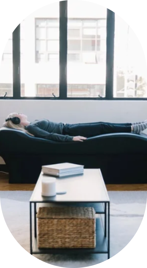 Person resting on dark sofa near large windows in bright modern wellness space