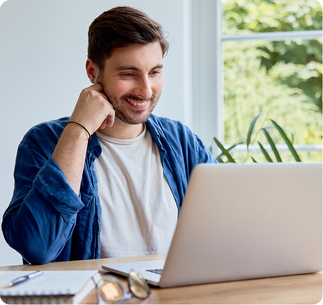 Man smiling at laptop while researching financing options at home