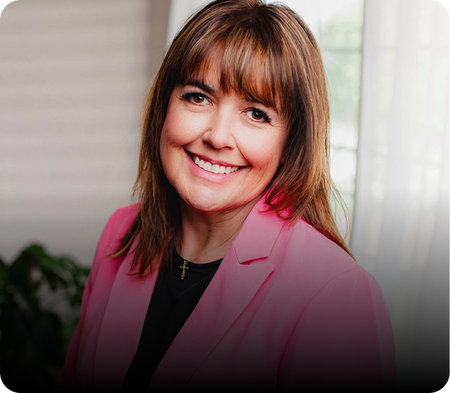 Woman in pink blazer smiling at camera in bright office setting