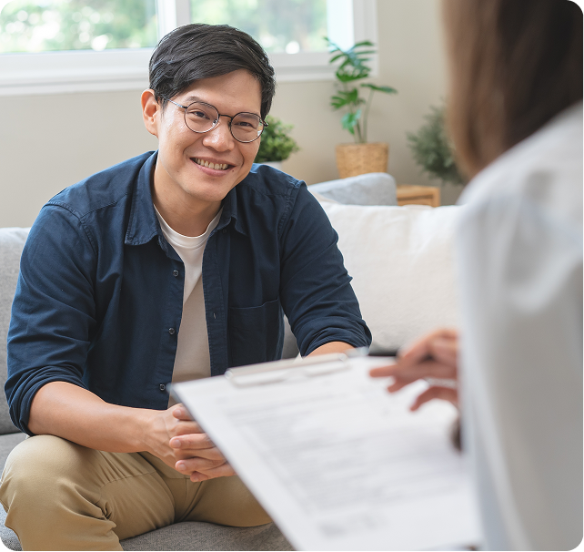 Smiling patient in blue shirt completing psychiatric evaluation form with healthcare provider in office