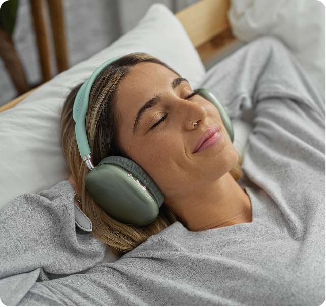 Woman relaxing on treatment bed wearing green vibration therapy headphones around neck