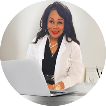 Female doctor in white coat working on laptop at desk