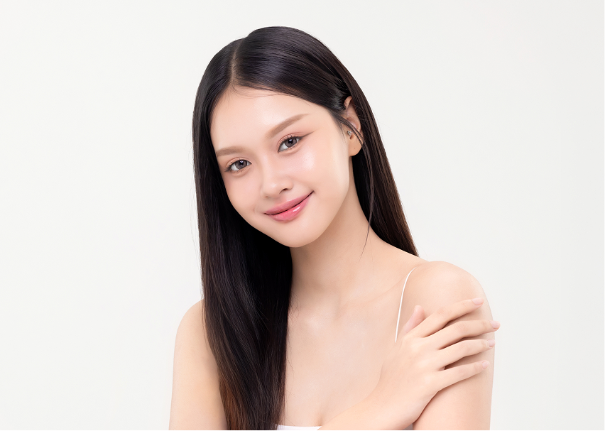 Woman with long straight black hair touching shoulder, smiling at camera