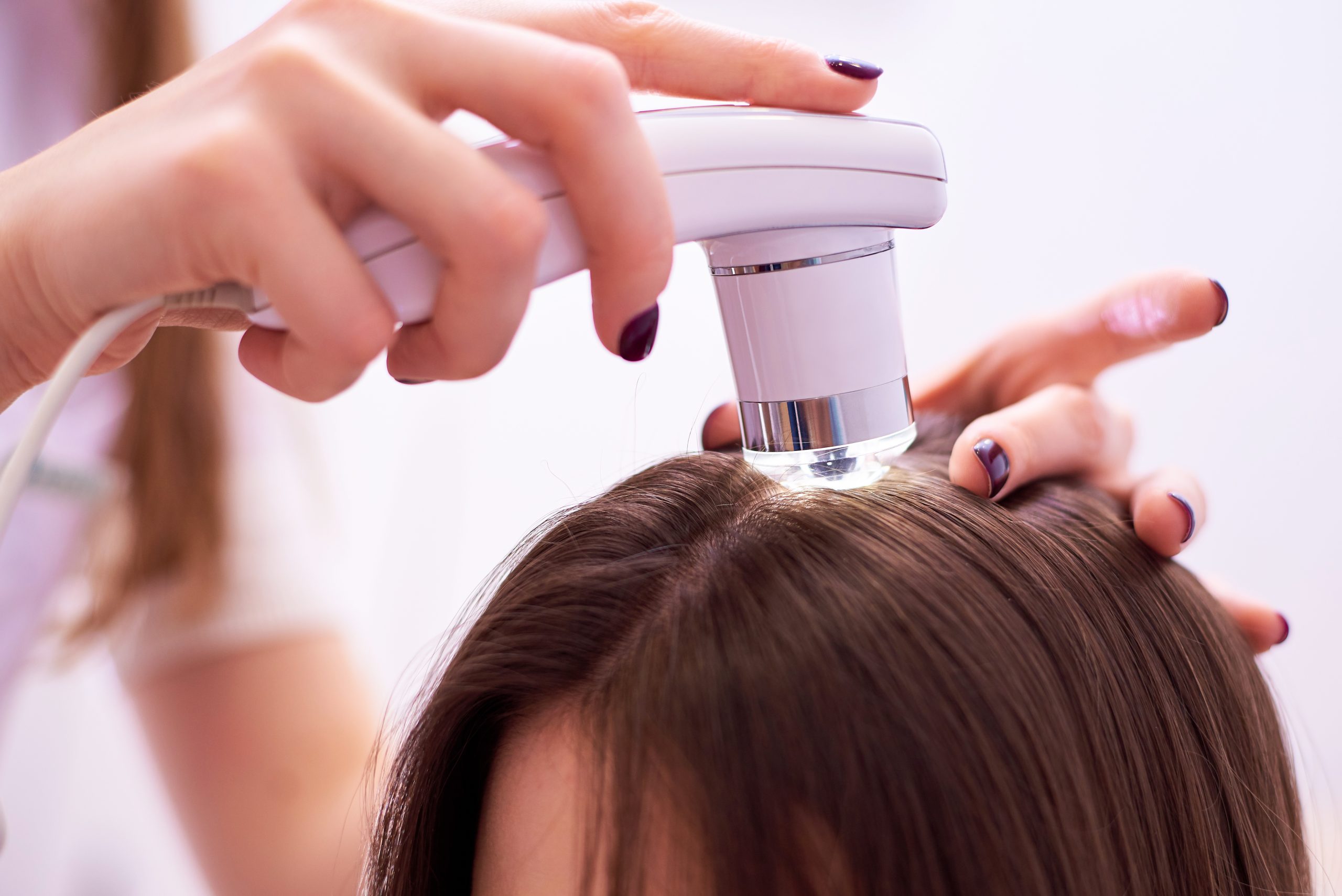 Person dispensing product from white scalp applicator onto hair roots