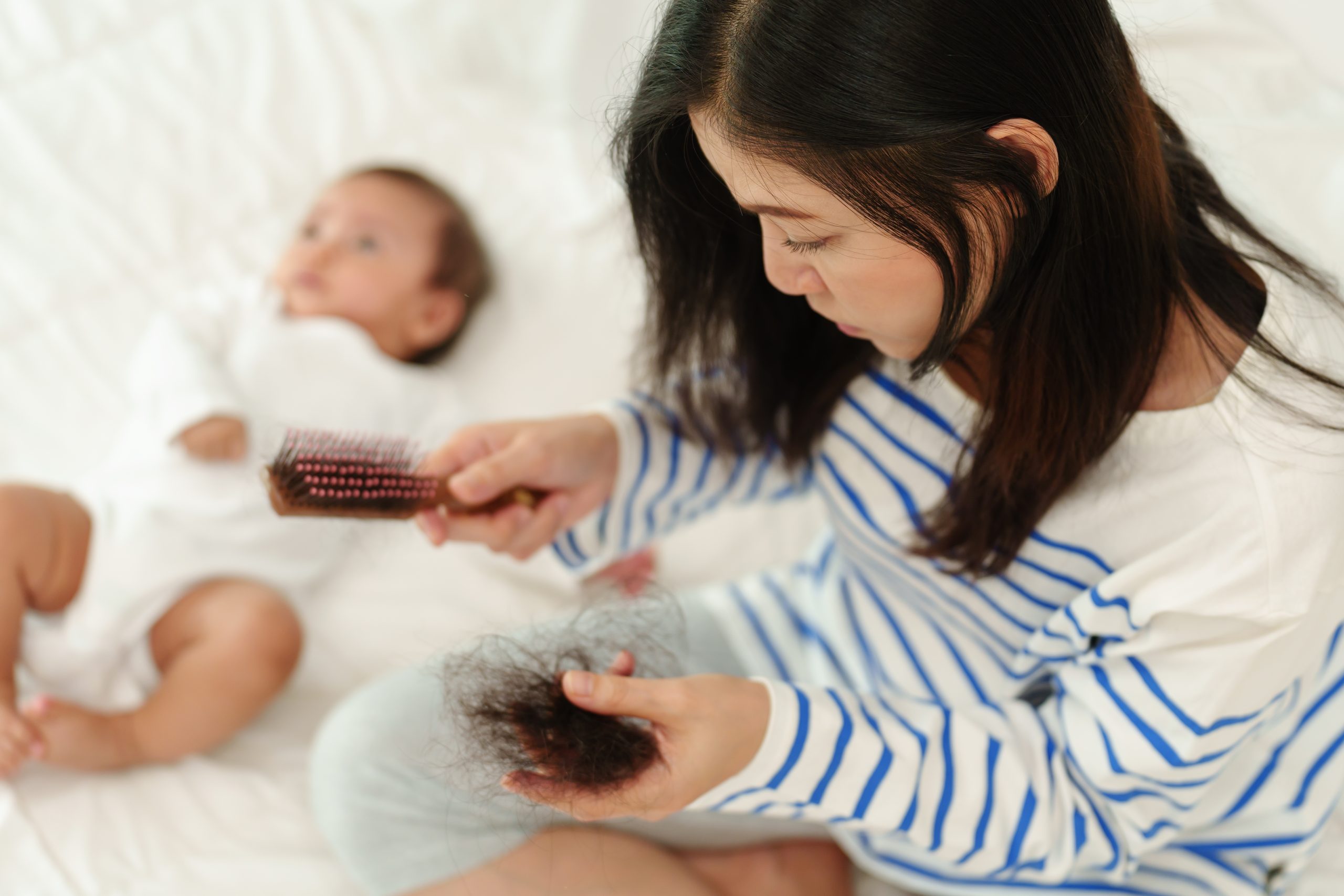 Woman brushing baby's hair with brush collecting loose strands