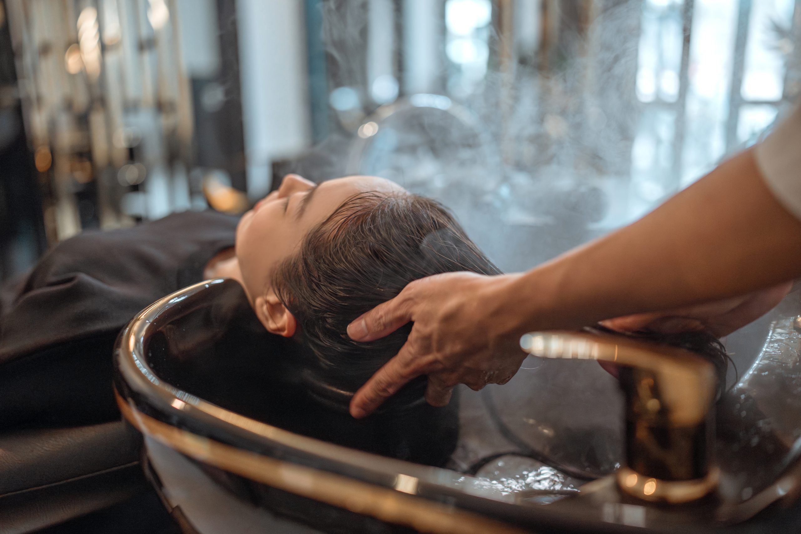 Therapist massaging client's head and scalp during salon treatment