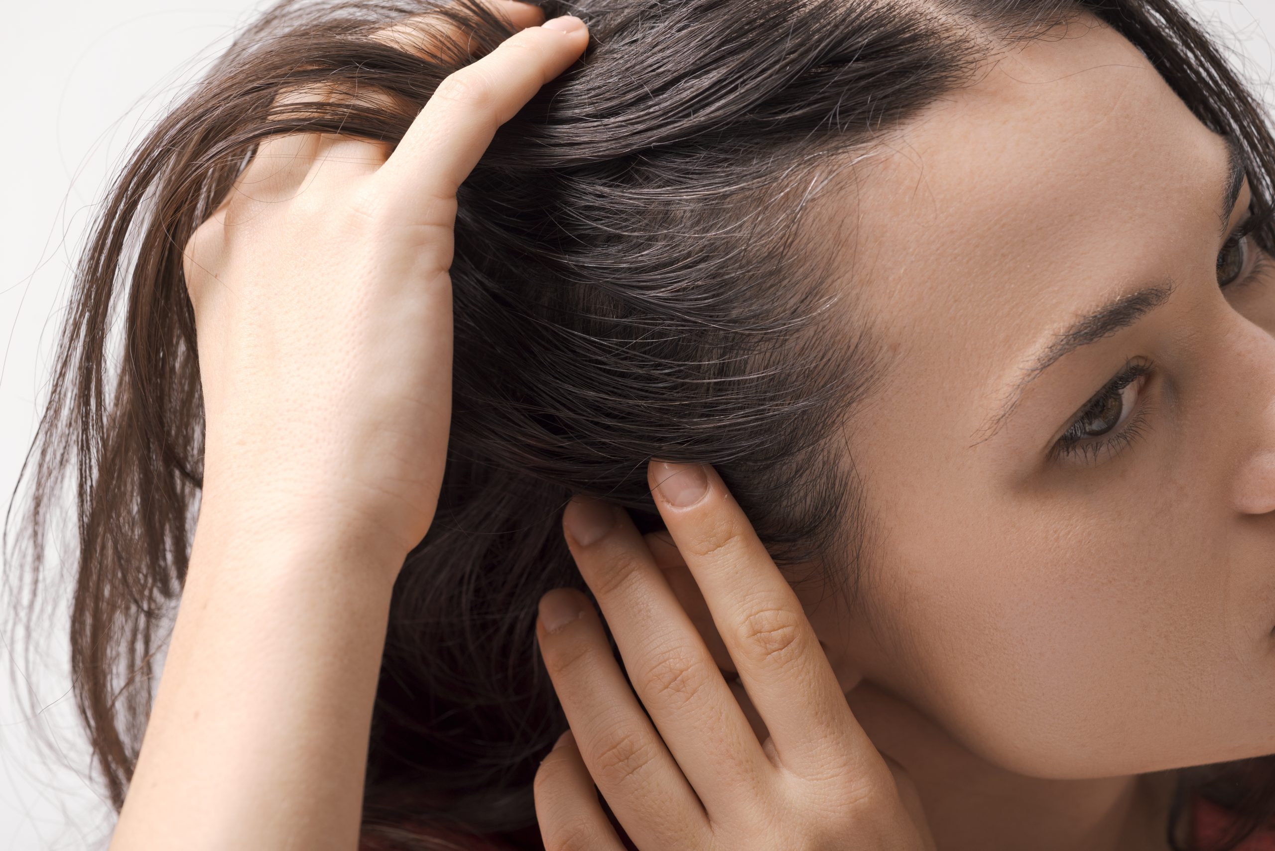 Woman touching and examining her hair, checking scalp condition