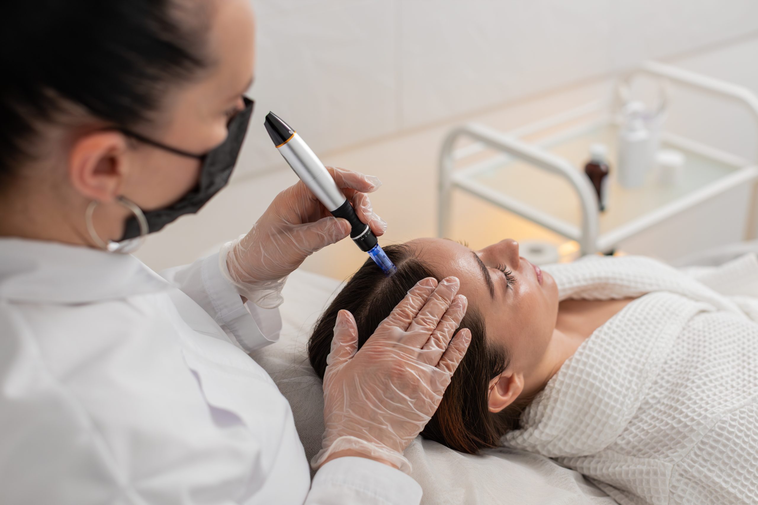 Specialist using handheld device to assess scalp condition during treatment
