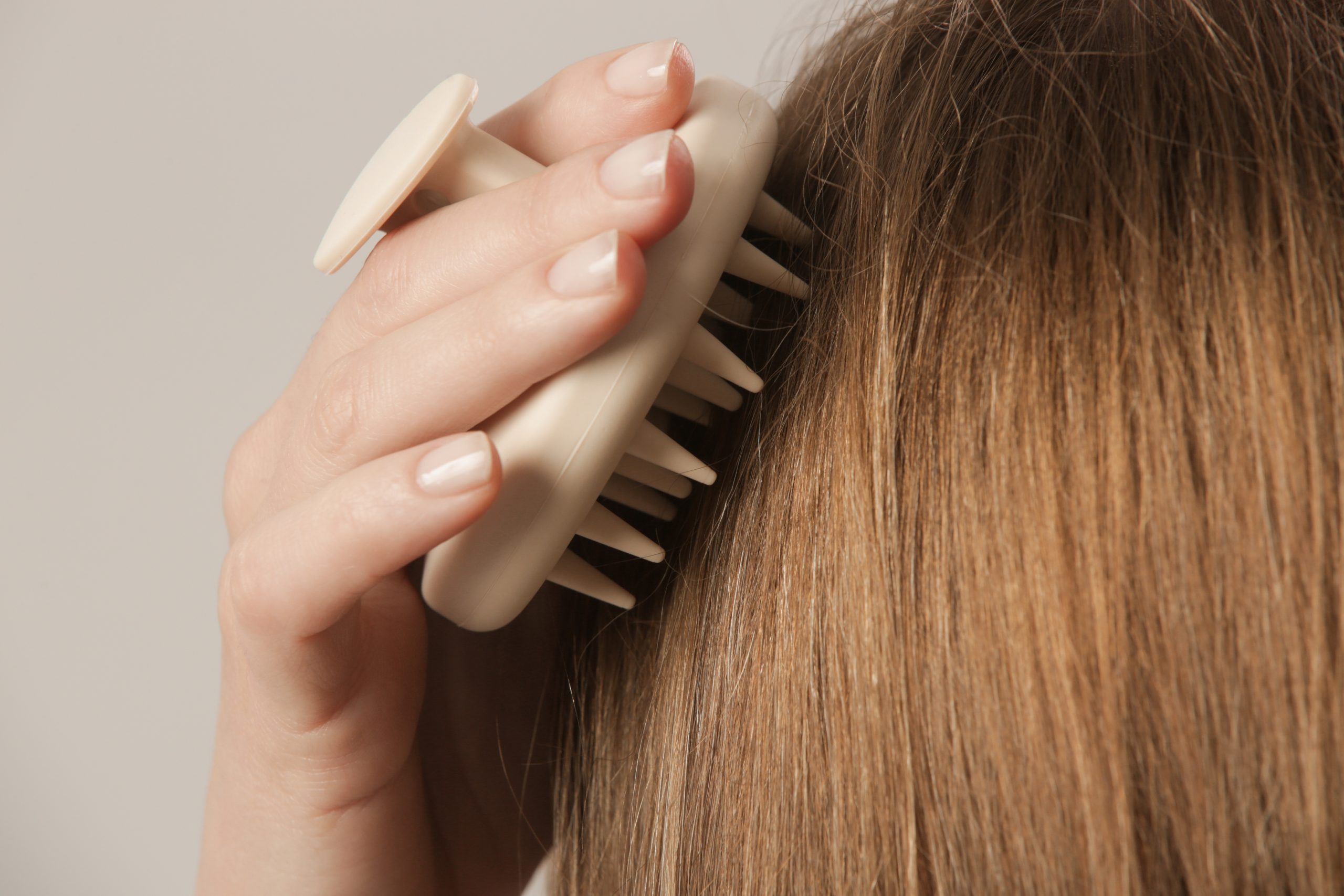 Hand brushing through long brown hair with a paddle brush