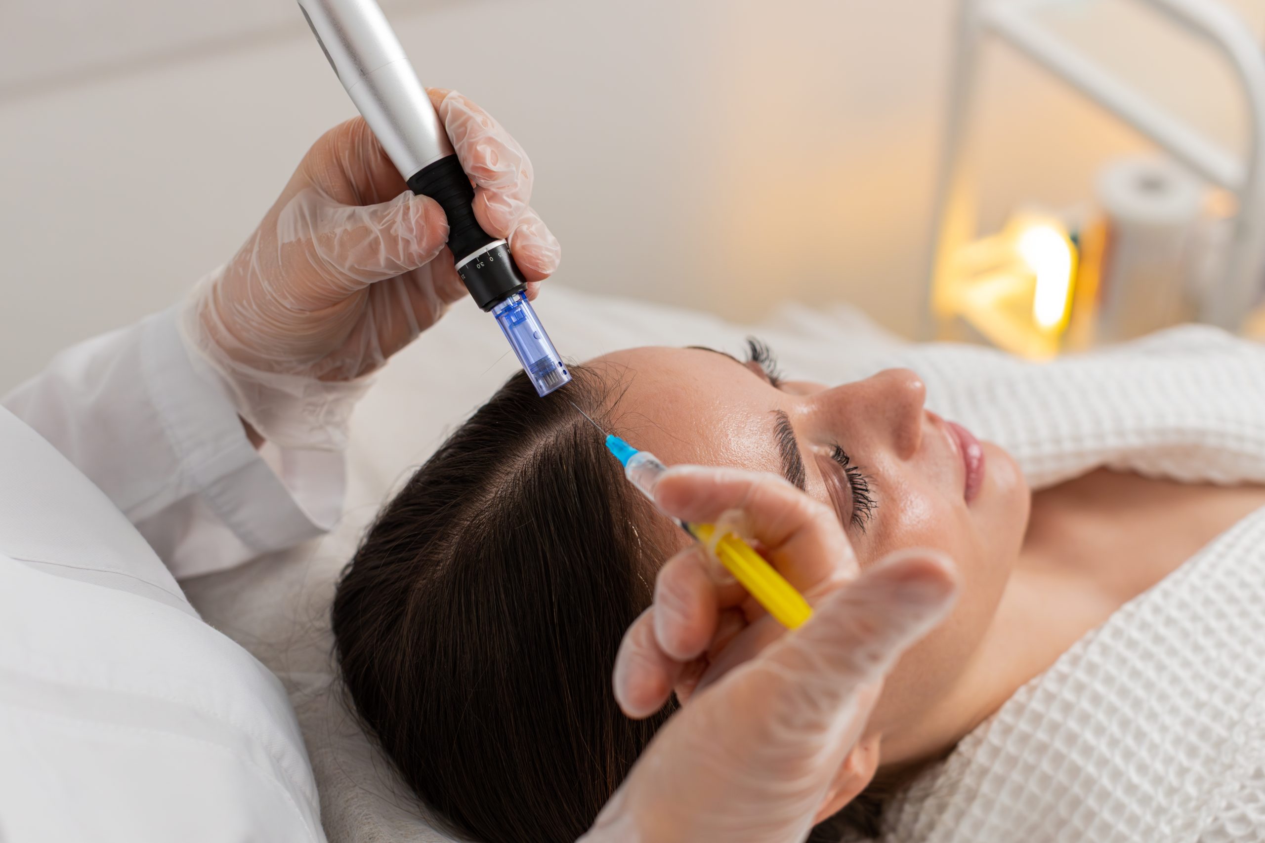Clinician applying colored serums to a patient's scalp with a handheld applicator during a treatment