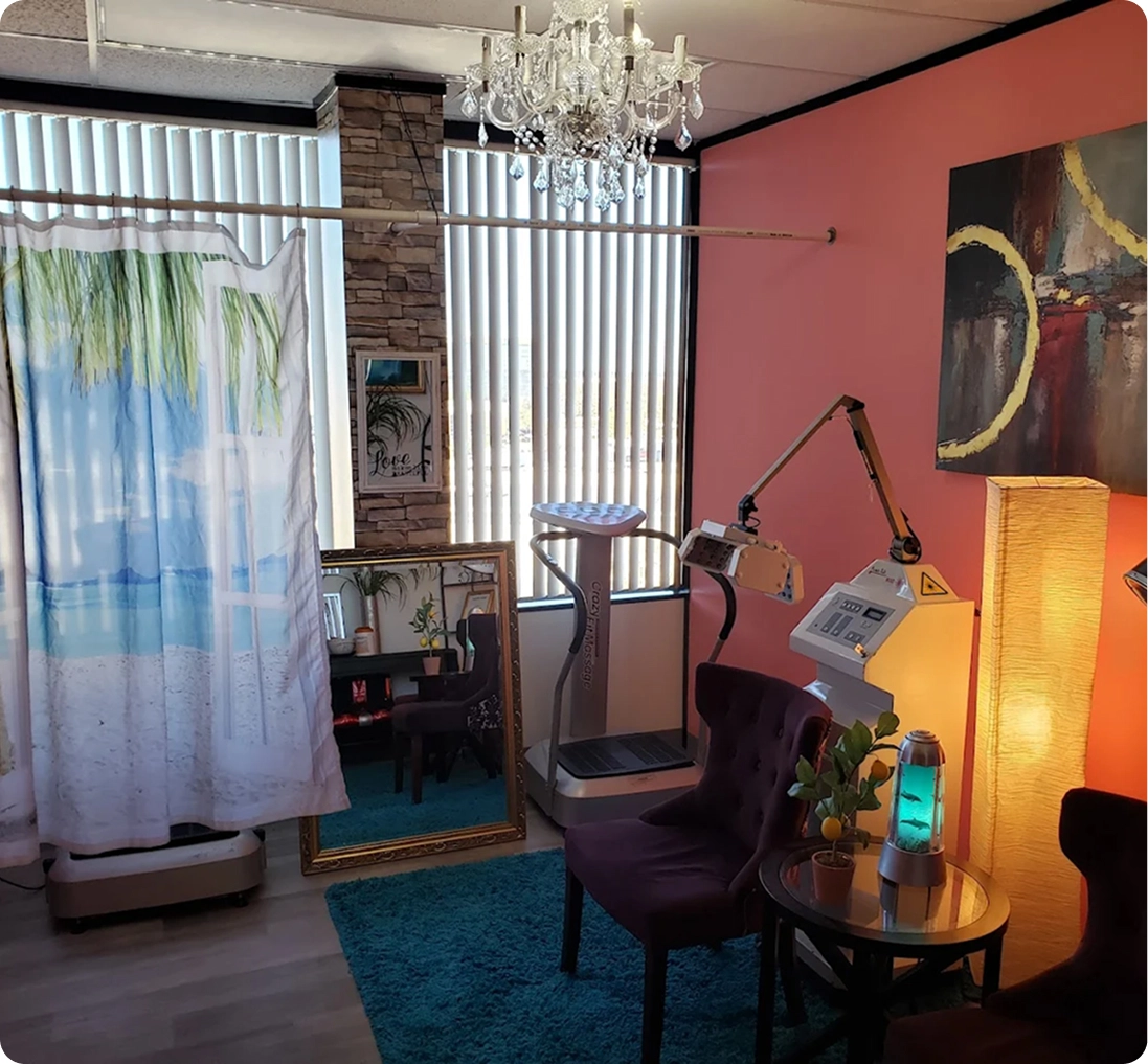 Scalp treatment room with pink walls, crystal chandelier, adjustable treatment chair, and specialized scalp therapy equipment