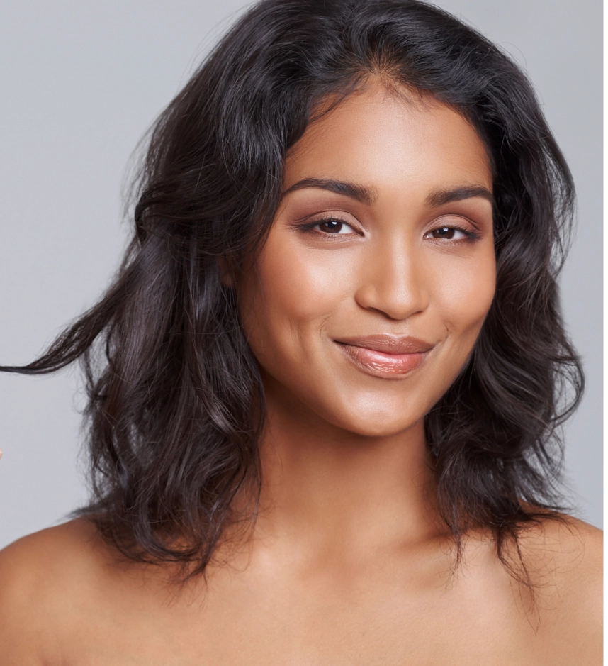 Woman with wavy dark hair and healthy skin looking at camera