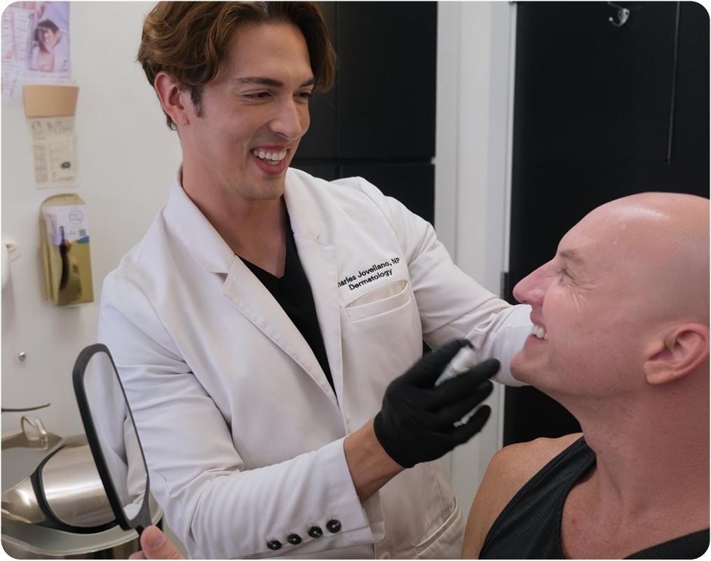 Dermatologist holding handheld device examining male patient's face during consultation