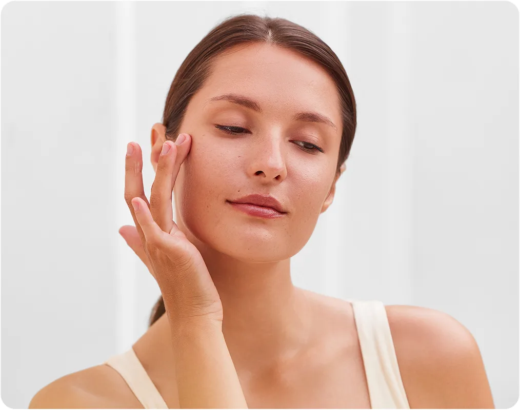 Woman touching cheek with eyes closed, displaying facial skin