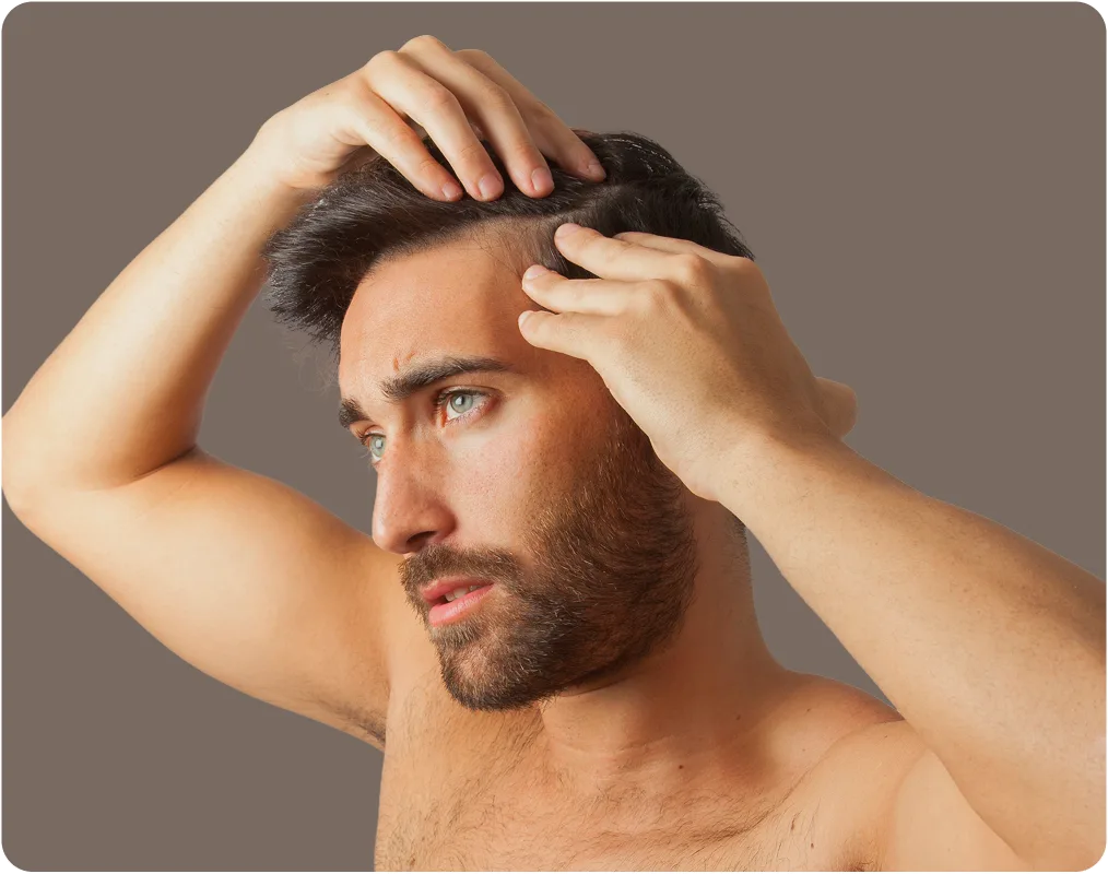 Man examining his hairline with both hands, showing receding hair