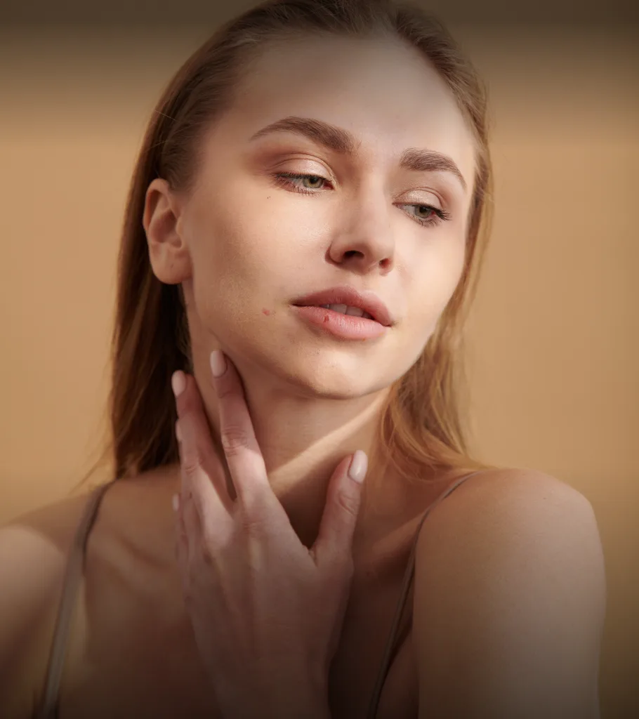 Woman touching her face and jawline against neutral background