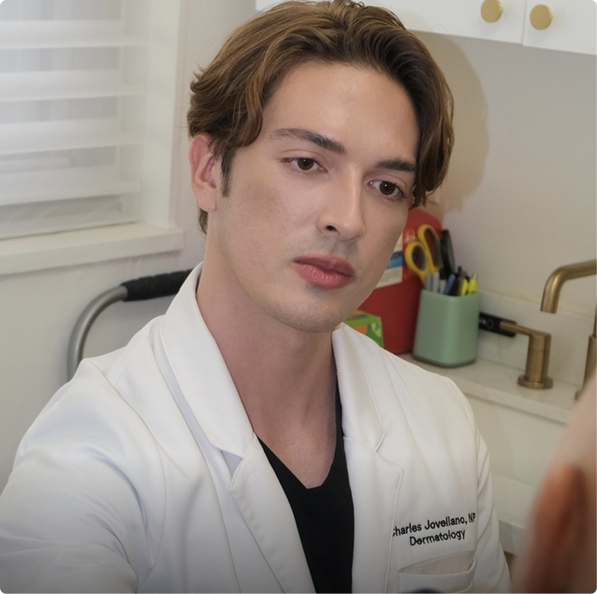 Dermatologist Charles Javellana in white coat at bathroom sink during consultation