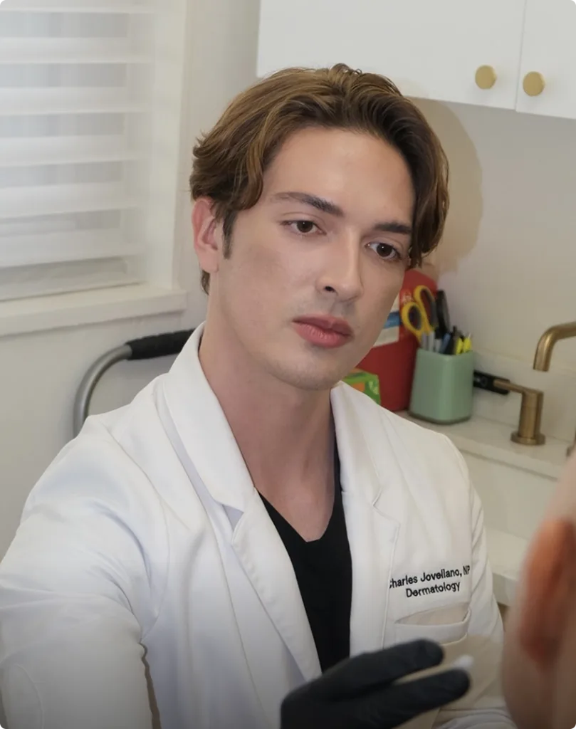 Dermatologist Charles Jovaliano in white coat at clinic desk