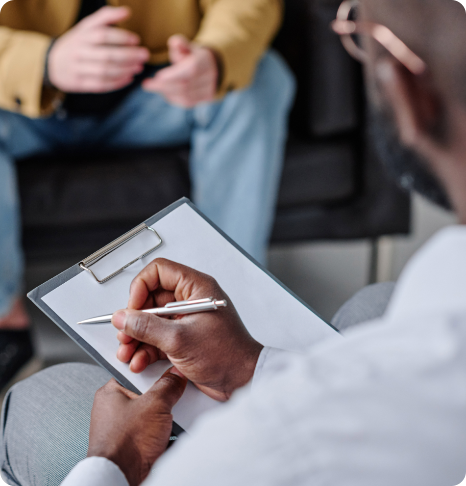 Mental health professional taking notes on clipboard while meeting with patients in background