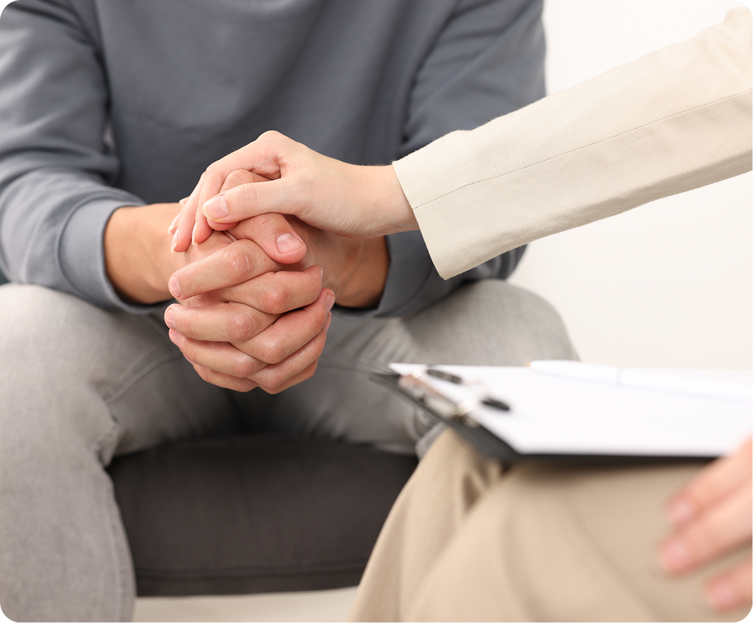 Two professionals joining hands together in supportive gesture at desk