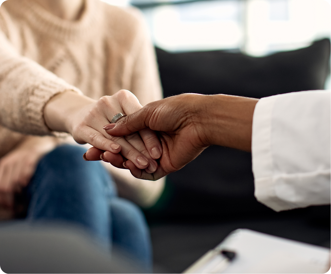 Two people placing hands together in supportive gesture during consultation