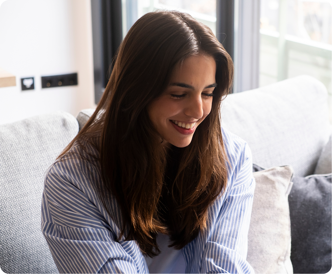 Woman smiling while seated on a couch in a bright room