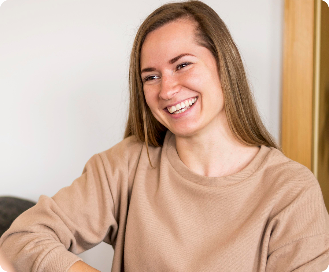 Woman smiling brightly while sitting indoors near wooden wall paneling