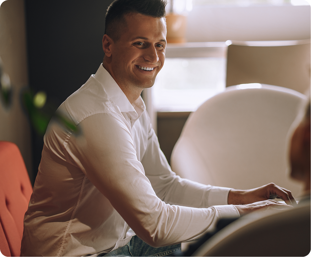 Man in white shirt smiling at desk in modern office setting