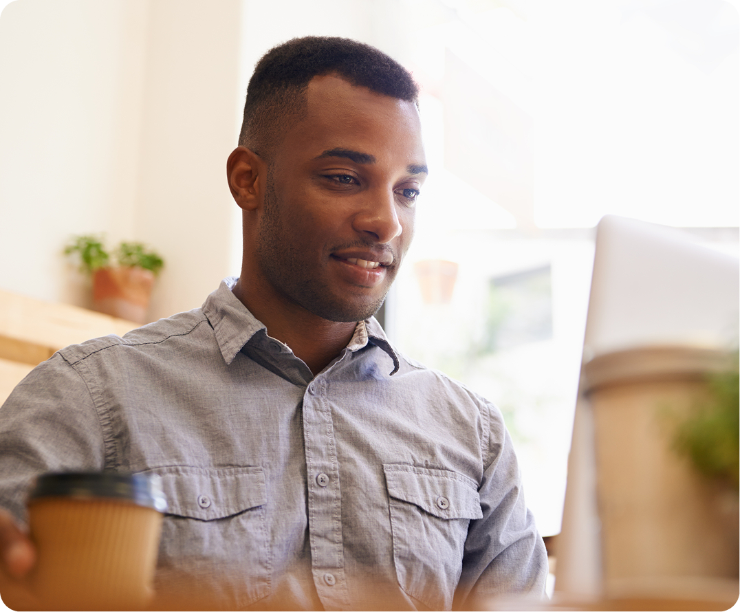 Man in gray button-up shirt smiling while looking at computer monitor in office