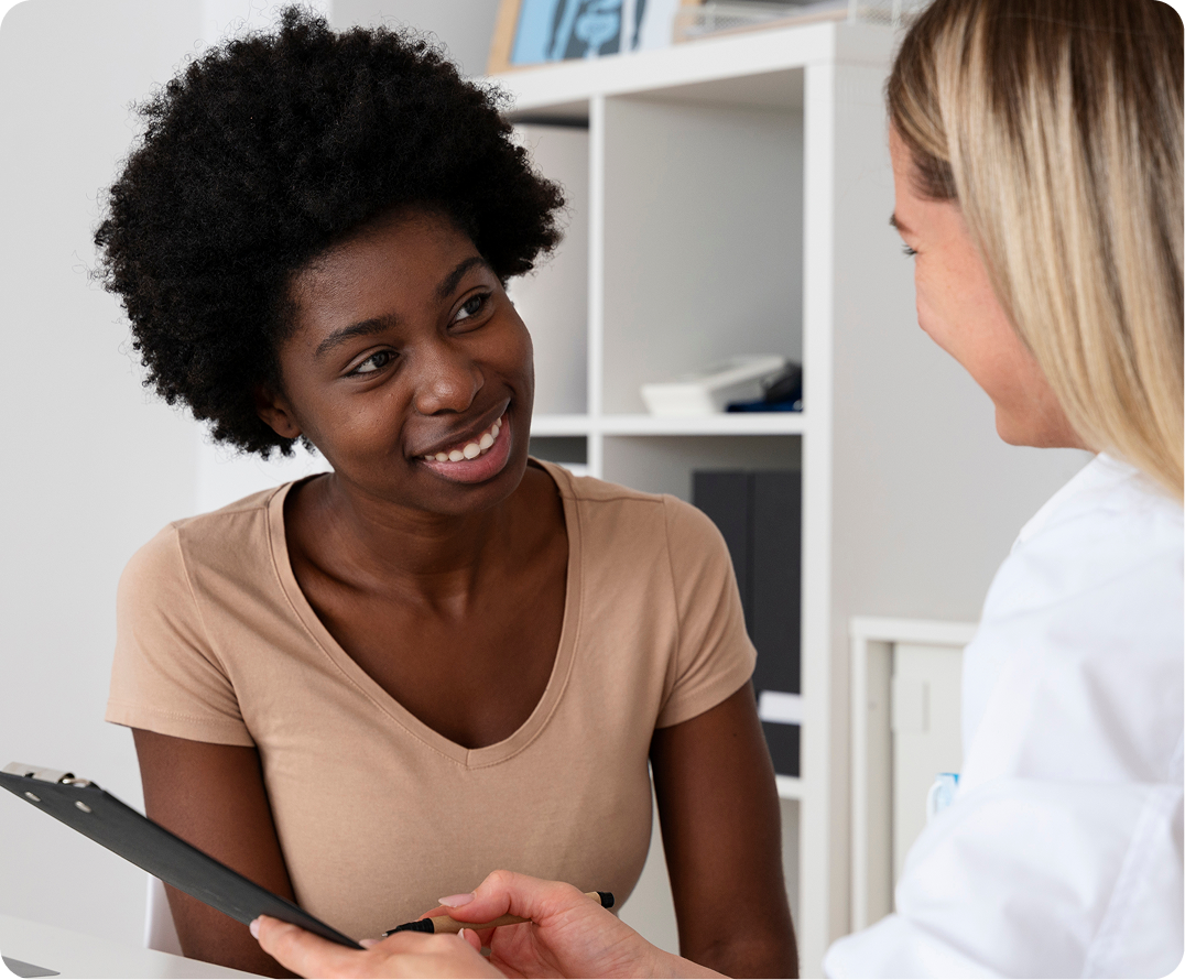 Healthcare provider in white coat discussing clipboard with smiling patient