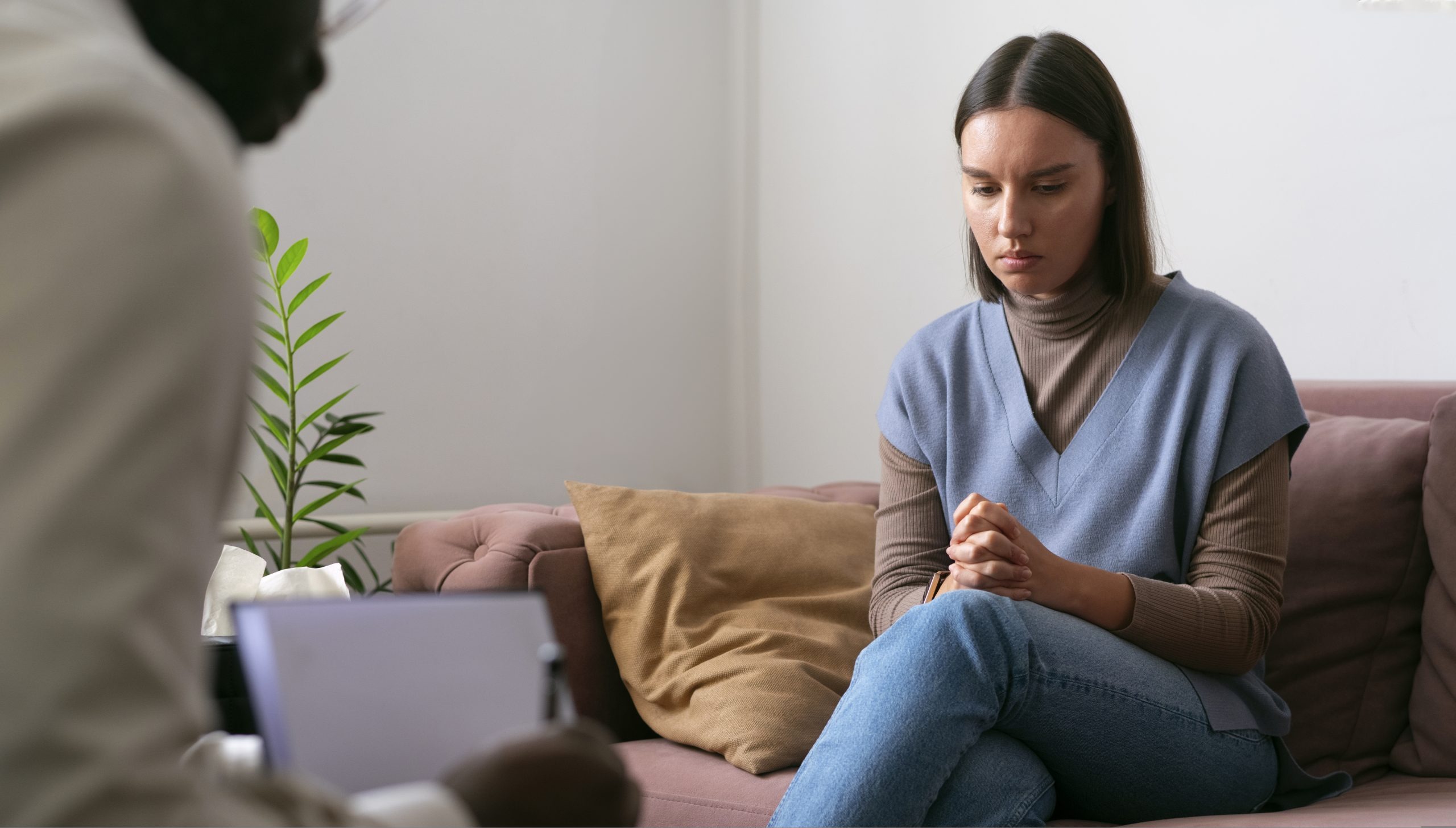 Woman sitting on a couch looking down during a therapy session with a counselor