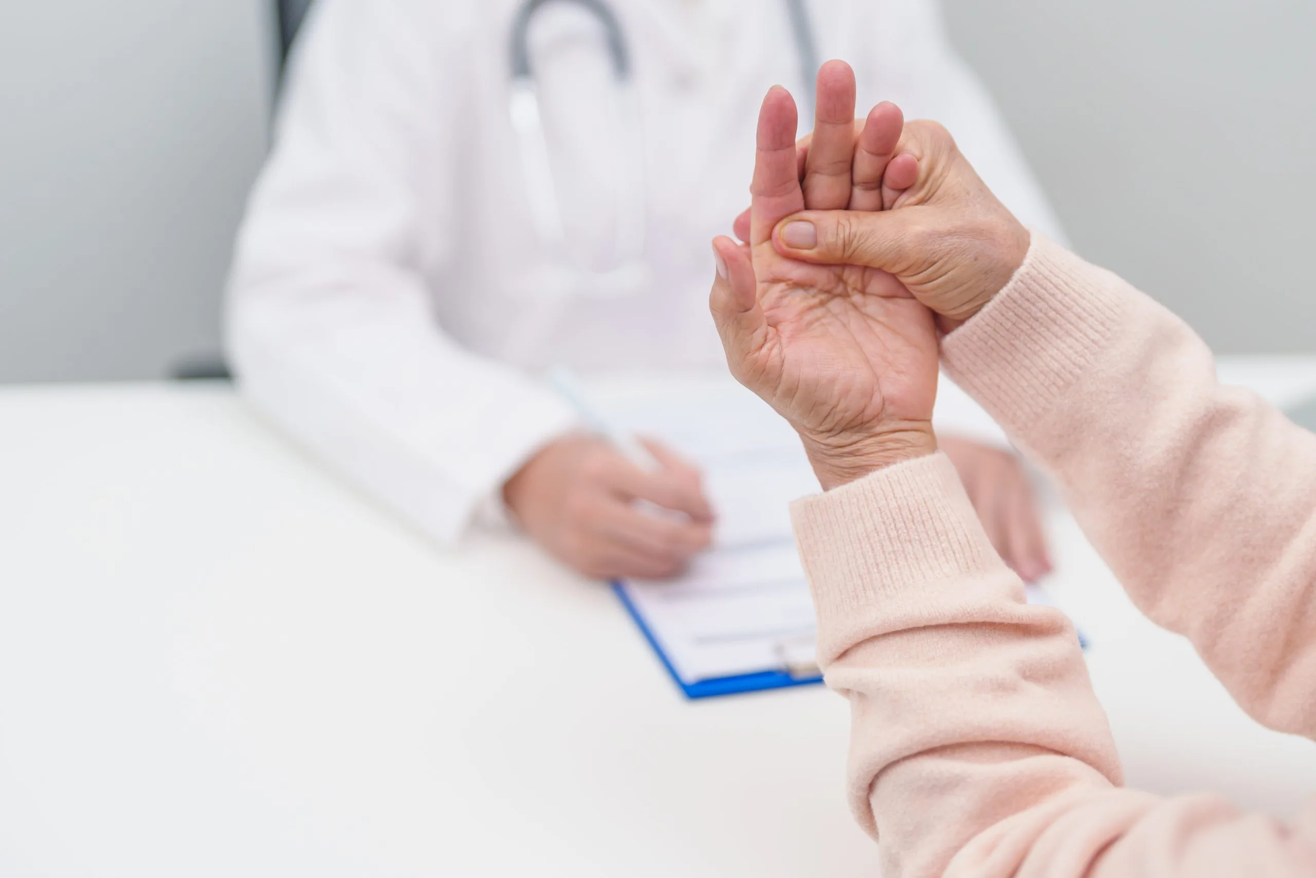 Patient's hand raised during consultation with healthcare provider in white coat