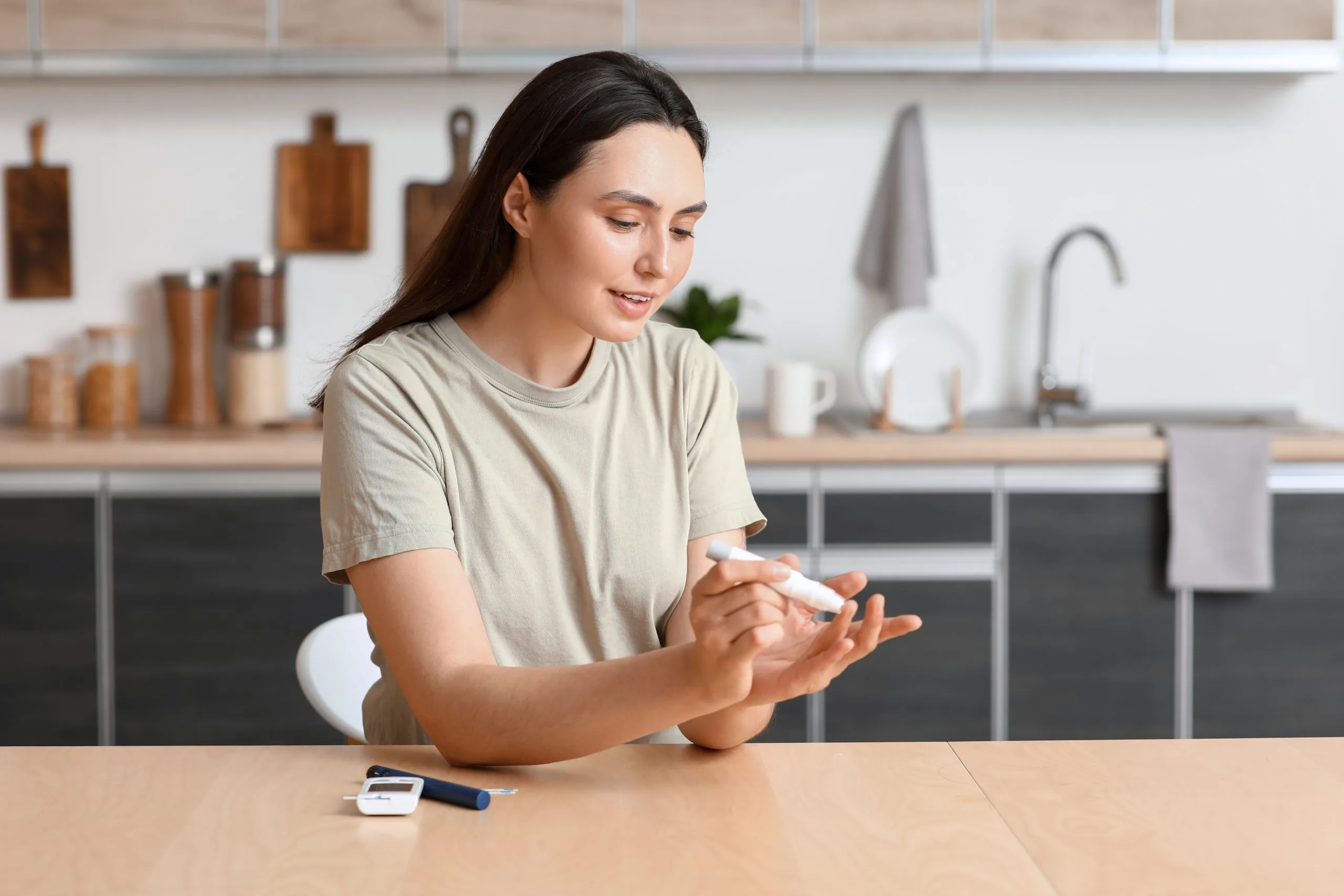 Woman in kitchen checking blood glucose with a fingerstick test kit