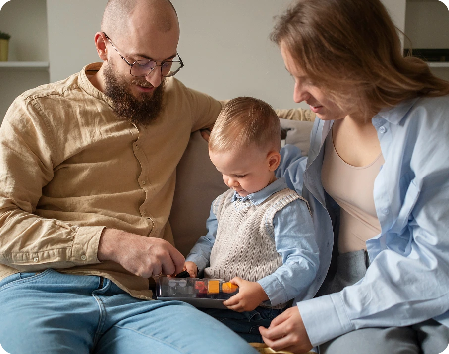 Parents and toddler playing with building blocks together on a couch