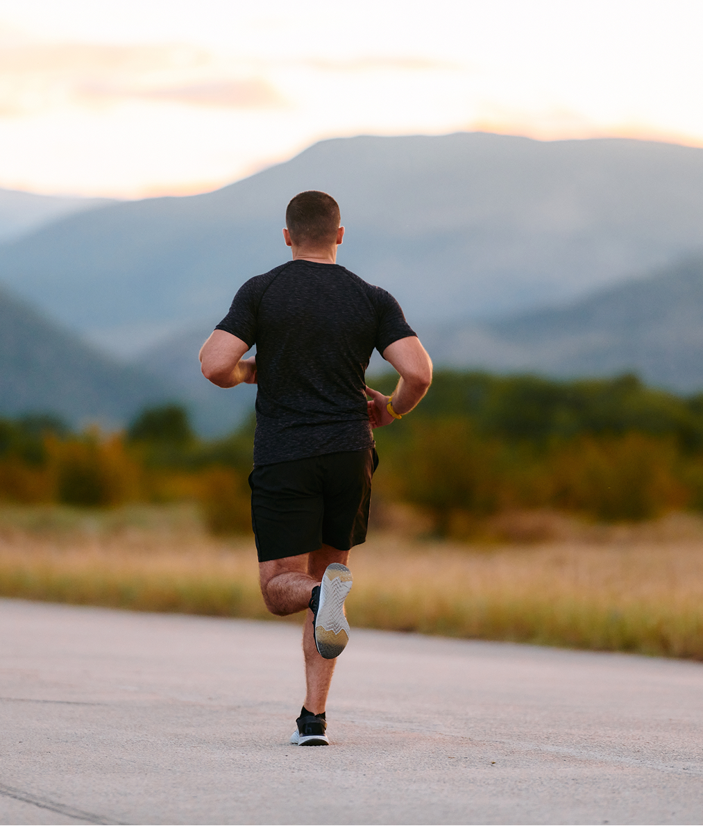 Man jogging on road with mountains in blurred background